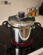 Falez 7-liter stainless steel pressure cooker made in Turkey sitting on a black stovetop, showing steam venting and food cooking inside, available at ONEMORE.