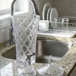 Elegant One More 4.5 liter diamond-cut glass beverage dispenser with a silver spigot and decorative lid, filled with lemon-infused water on a table setting.