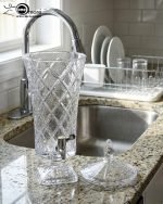 Elegant One More 4.5 liter diamond-cut glass beverage dispenser with a silver spigot and decorative lid, filled with lemon-infused water on a table setting.