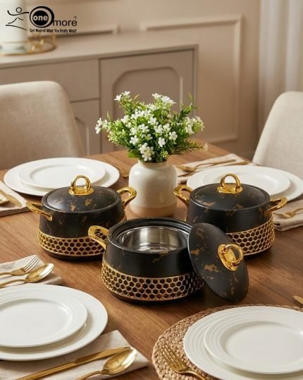 Three One More branded insulated hotpots in black and white marble finishes with gold honeycomb detailing and gold handles, shown in a kitchen and dining room setting with steaming food.