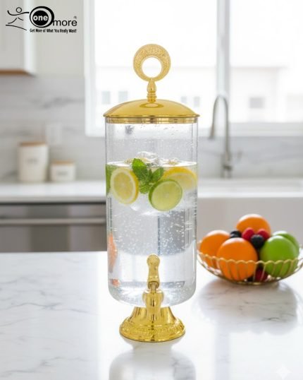 Elegant 3.5L clear glass water dispenser with luxury gold base, gold lid with ring handle, and a gold spigot, filled with infused water and citrus slices on a marble kitchen countertop.