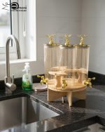 Triple 5.5L shaded glass beverage dispenser featuring gold deer-topped lids and gold taps, mounted on a 360-degree rotating wooden stand for elegant serving.