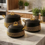 A luxury set of three insulated hotpot food warmers in matte black and white finishes featuring decorative gold hexagonal trim and polished gold handles, displayed in kitchen, dining, and outdoor settings.