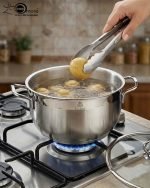 Stacked collection of Falez stainless steel cooking pots in seven sizes ranging from 18cm to 30cm, featuring glass lids and a polished silver finish, displayed on a wooden table for the One More kitchenware brand.