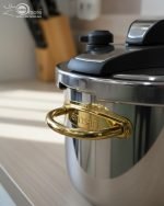 Stainless steel 6-liter pressure cooker with elegant gold handles and black safety locking lid, releasing steam on a stovetop, filled with beef stew – FALEZ kitchenware collection.