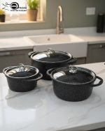 Falez 9-piece black granite non-stick cookware set including deep pots, shallow casserole, and fry pan with glass lids, displayed on a marble kitchen countertop.