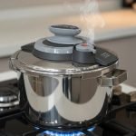 6-liter stainless steel pressure cooker made in Turkey with silver handles, shown steaming on a gas stovetop with fresh vegetables.