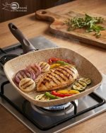 Falez square granite non-stick grill pan cooking grilled chicken breast and vegetables with perfect char marks, featuring a beige speckled finish and ergonomic brown handle.