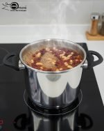 Falez 7-liter stainless steel pressure cooker made in Turkey sitting on a black stovetop, showing steam venting and food cooking inside, available at ONEMORE.