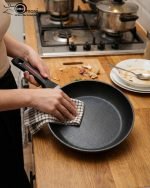 One More 24cm non-stick granite fry pan with silicone handle cooking eggs on a stovetop, featuring durable granite coating for low-oil cooking.