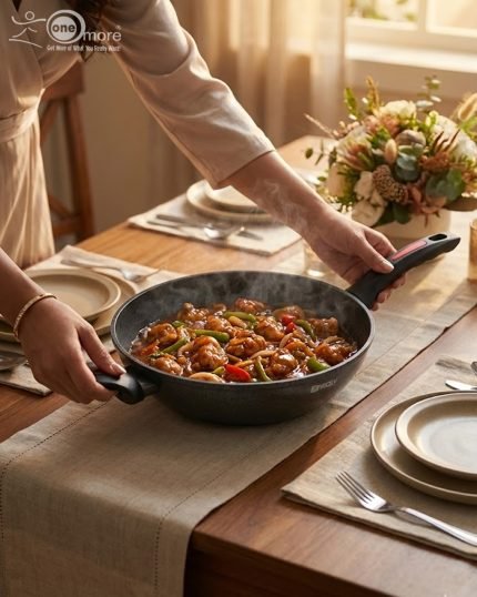 One More 24cm granite non-stick wok with glass lid and black silicon handle, displaying healthy low-oil cooking with fresh vegetables in the background.