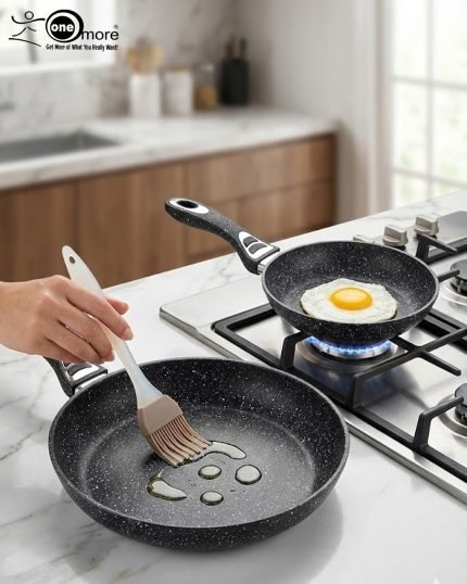 Stack of One More black granite non-stick cooking pots in four sizes (22cm, 24cm, 26cm, and 28cm) with ergonomic handles, displaying a premium speckled texture.