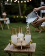 Triple 5.5L shaded glass beverage dispenser featuring gold deer-topped lids and gold taps, mounted on a 360-degree rotating wooden stand for elegant serving.