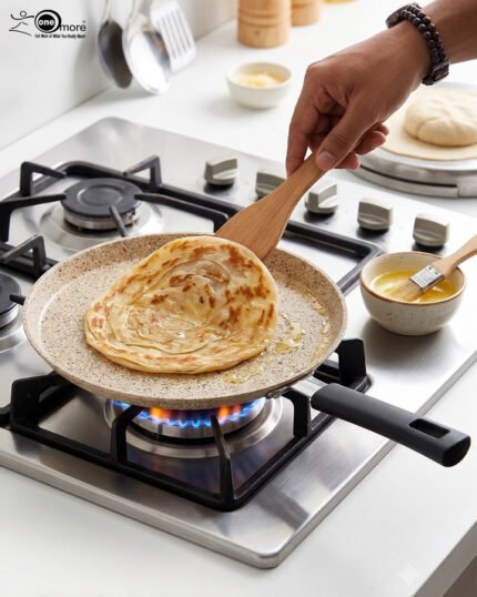 Falez non-stick granite crepe pan in beige speckled finish, shown cooking a golden-brown crepe on a gas stove with a wooden spreader. Option 2: Person flipping a crepe in a Falez granite coated pan, demonstrating non-stick surface and low-oil cooking capabilities.