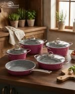 Falez 9-piece purple granite cookware set arranged on a kitchen counter, featuring non-stick deep pots, a shallow casserole with glass lids, and a frying pan with food cooking inside, Made in Turkey.