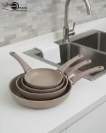 O.M.S premium granite non-stick fry pan made in Turkey, shown cooking vegetables with minimal oil usage and featuring a durable speckled beige finish.