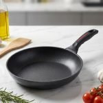 One More 24cm non-stick granite fry pan with silicone handle cooking eggs on a stovetop, featuring durable granite coating for low-oil cooking.