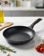 One More 24cm non-stick granite fry pan with silicone handle cooking eggs on a stovetop, featuring durable granite coating for low-oil cooking.
