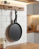 Non-stick 24cm granite crepe pan by One More in black speckled texture, showing a pancake being flipped with a wooden spatula on a gas stove.