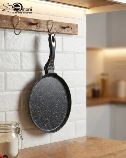 Non-stick 24cm granite crepe pan by One More in black speckled texture, showing a pancake being flipped with a wooden spatula on a gas stove.