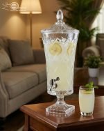 Elegant One More 4.5 liter diamond-cut glass beverage dispenser with a silver spigot and decorative lid, filled with lemon-infused water on a table setting.