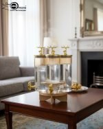Triple 5.5L shaded glass beverage dispenser featuring gold deer-topped lids and gold taps, mounted on a 360-degree rotating wooden stand for elegant serving.
