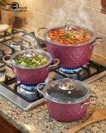 Falez 9-piece purple granite cookware set arranged on a kitchen counter, featuring non-stick deep pots, a shallow casserole with glass lids, and a frying pan with food cooking inside, Made in Turkey.