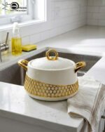 A luxury set of three insulated hotpot food warmers in matte black and white finishes featuring decorative gold hexagonal trim and polished gold handles, displayed in kitchen, dining, and outdoor settings.