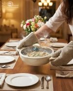 Falez 9-piece cream colored non-stick cookware set displayed on a wooden table, featuring a granite ceramic interior, glass lids with blue knobs, and a frying pan, made in Turkey.