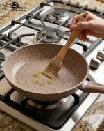 O.M.S premium granite non-stick fry pan made in Turkey, shown cooking vegetables with minimal oil usage and featuring a durable speckled beige finish.