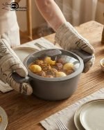 UCC LIFE 9-piece non-stick granite cookware set arranged on a wooden kitchen counter, featuring a frying pan, shallow casserole, and three pots with glass lids in a speckled grey finish.
