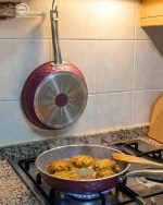 Falez 9-piece purple granite cookware set arranged on a kitchen counter, featuring non-stick deep pots, a shallow casserole with glass lids, and a frying pan with food cooking inside, Made in Turkey.