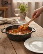 Falez 9-piece black granite non-stick cookware set including deep pots, shallow casserole, and fry pan with glass lids, displayed on a marble kitchen countertop.