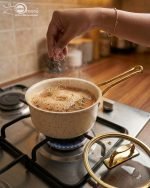 Falez 9-piece cream granite non-stick cookware set with gold handles, featuring a fry pan, sauce pan, and casseroles with glass lids, made in Turkey for healthy low-oil cooking.