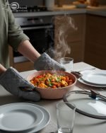 Falez 9-piece pink granite non-stick cookware set including 3 cooking pots with lids, 1 shallow casserole with lid, and 1 frying pan displayed on a kitchen counter and dining table, demonstrating healthy low-oil cooking with steam rising from hot food.