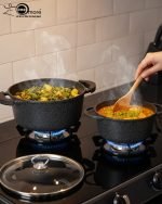 Falez 9-piece black granite non-stick cookware set including deep pots, shallow casserole, and fry pan with glass lids, displayed on a marble kitchen countertop.