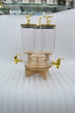 Elegant triple glass beverage dispenser set on a rotating wooden stand, featuring gold-toned taps and decorative deer figurines on lids, shown in various settings including a dinner party and outdoor event.