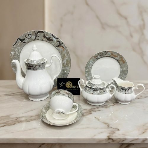 A 24-piece white ceramic tea set featuring grey marble-textured borders and elegant filigree accents, displayed on a marble surface.