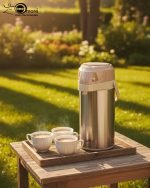 3-Liter Stainless Steel Airpot Thermos Flask with pump action dispenser and glass liner, displayed on a kitchen counter in Blue, Brown, and Green color options. Features callouts for rotating base, air-tight cap, and sleek handle.