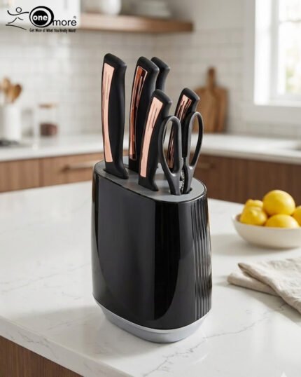 A 7-piece OneMore kitchen knife set featuring stainless steel blades and ergonomic black handles with rose gold accents, displayed both inside and next to a modern black ribbed knife block on a white marble countertop.