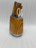 A 6-piece stainless steel kitchen knife set with light brown wood-grain handles and white kitchen shears, displayed both inside and next to a matching oval wood-patterned storage block on a granite countertop.