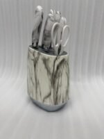 A 6-piece kitchen knife set featuring white and grey marble-patterned handles and a matching oval storage block, displayed on a granite countertop.