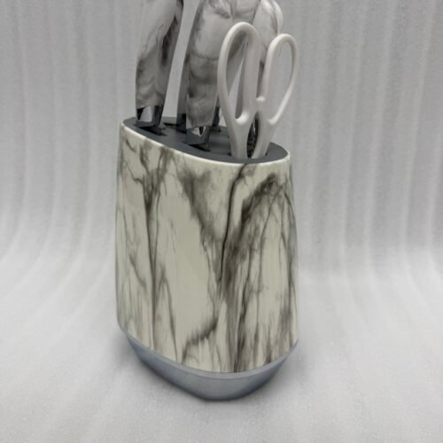 A 6-piece kitchen knife set featuring white and grey marble-patterned handles and a matching oval storage block, displayed on a granite countertop.