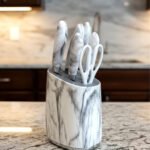 A 6-piece kitchen knife set featuring white and grey marble-patterned handles and a matching oval storage block, displayed on a granite countertop.