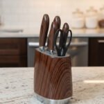 A 6-piece kitchen knife set featuring stainless steel blades with dark wood-grain patterned handles and a matching oval storage block on a granite countertop.