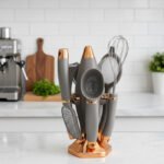 A professional 7-piece kitchen gadget set with rose gold and black ergonomic handles, featuring a pizza cutter, whisk, and grater, organized on a sleek black rotating stand.