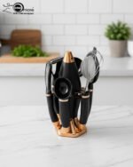 A premium 7-piece kitchen gadget set with rose gold and black handles, featuring a pizza cutter, whisk, and grater, organized on a sleek black rotating stand.