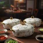 A set of three luxury marble-patterned insulated hotpots with gold handles and knobs, arranged on a wooden dining table with small bowls of condiments and a blurred restaurant BG.