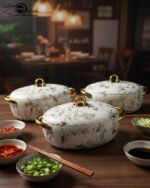A set of three luxury marble-patterned insulated hotpots with gold handles and knobs, arranged on a wooden dining table with small bowls of condiments and a blurred restaurant BG.
