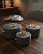 A set of three round, quilted insulated hotpots in varying sizes (1L, 2.5L, and 4L) with gold handles and lid accents, displayed on a kitchen counter and wooden dining table.
